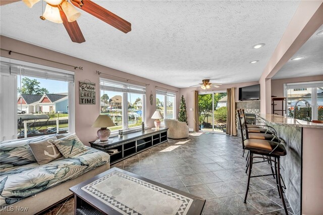 living room featuring a textured ceiling, sink, and ceiling fan