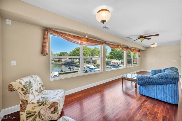 interior space featuring ceiling fan, dark wood-type flooring, and a water view