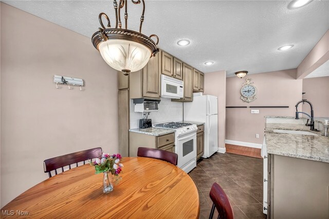 kitchen with a textured ceiling, white appliances, light stone countertops, and sink