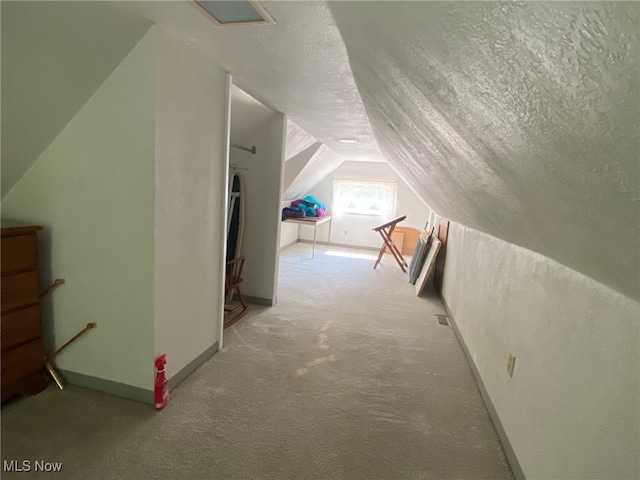 bonus room with carpet, vaulted ceiling, and a textured ceiling