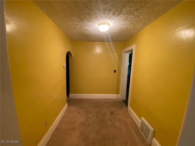 hallway with a textured ceiling and carpet