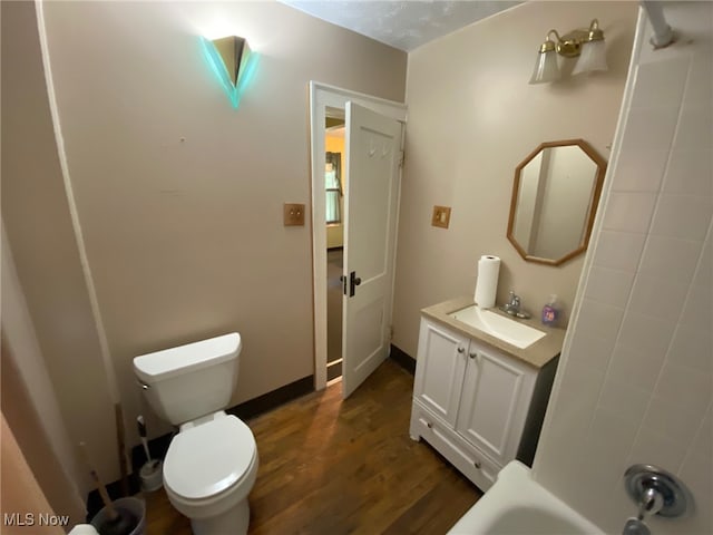 full bathroom featuring a textured ceiling, bathing tub / shower combination, hardwood / wood-style floors, vanity, and toilet