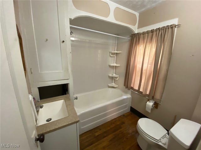 full bathroom featuring vanity, toilet, a textured ceiling,  shower combination, and hardwood / wood-style floors