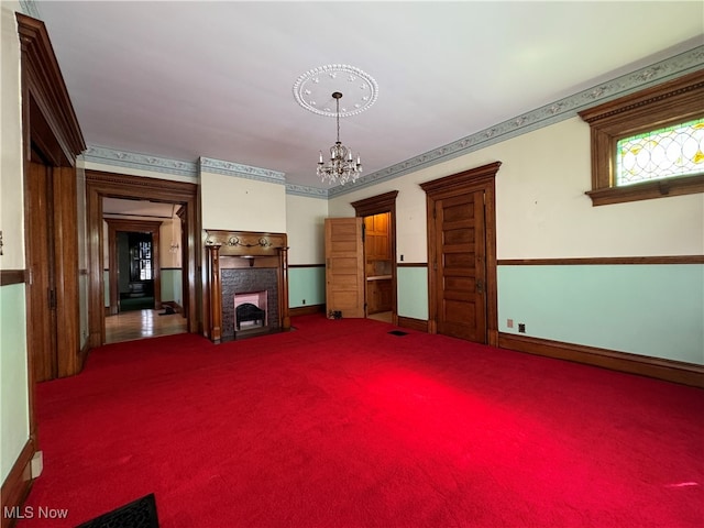 unfurnished living room with a chandelier, carpet flooring, and crown molding