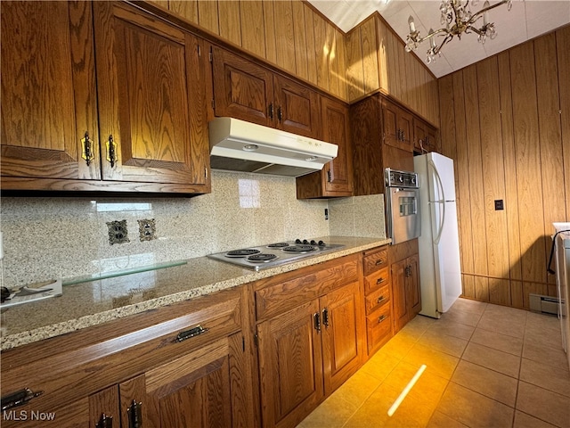 kitchen featuring tasteful backsplash, a notable chandelier, stainless steel appliances, light tile patterned floors, and light stone countertops