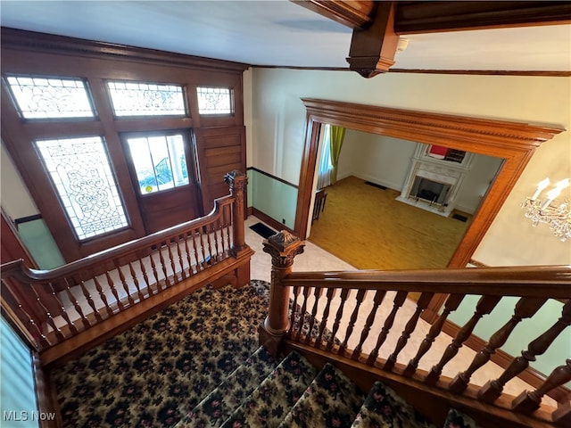 foyer featuring carpet flooring, a premium fireplace, and a notable chandelier