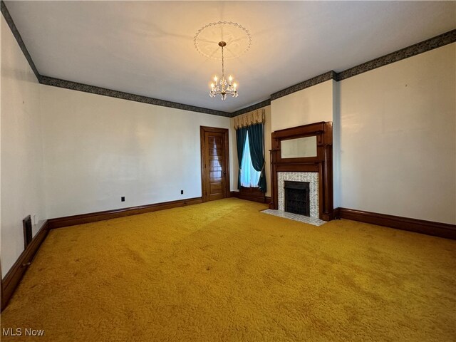 unfurnished living room featuring ornamental molding, a fireplace, carpet flooring, and an inviting chandelier