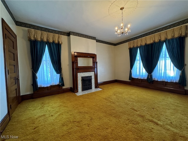 unfurnished living room with a notable chandelier, a tile fireplace, plenty of natural light, and carpet flooring