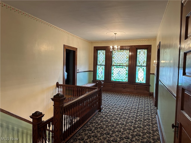 hallway with carpet and a chandelier