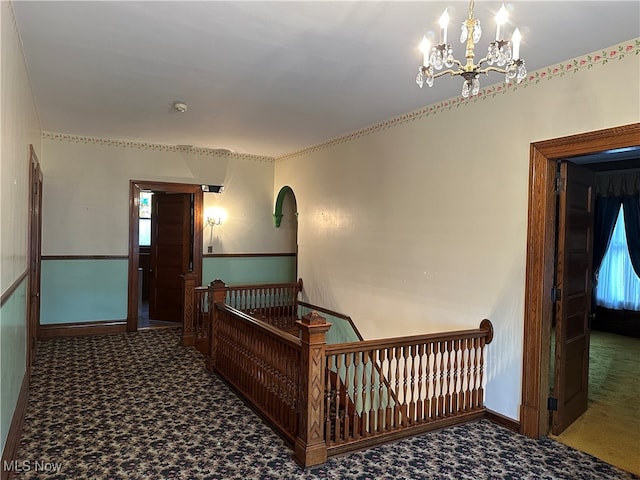 corridor with a notable chandelier and carpet floors