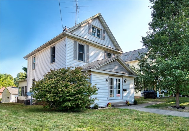 view of side of home with french doors, central AC unit, and a yard