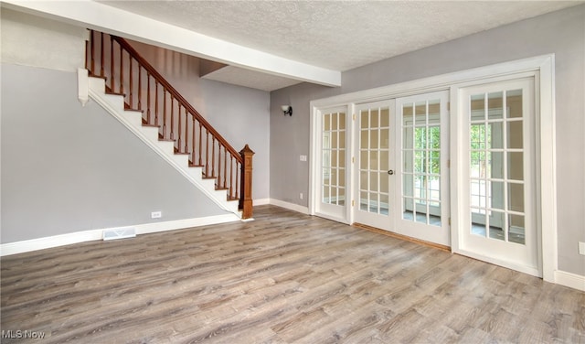 interior space with a textured ceiling, hardwood / wood-style flooring, and french doors