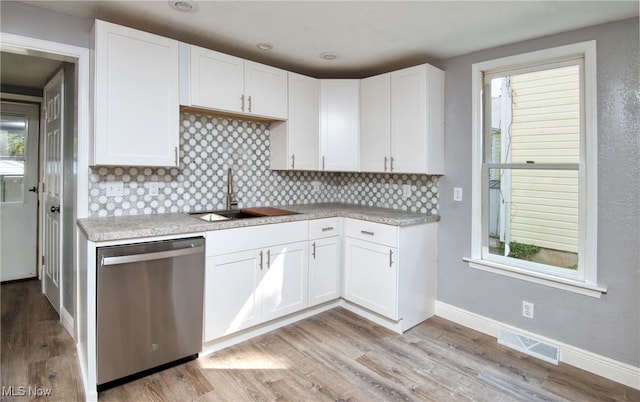 kitchen with dishwasher, sink, decorative backsplash, white cabinetry, and light wood-type flooring