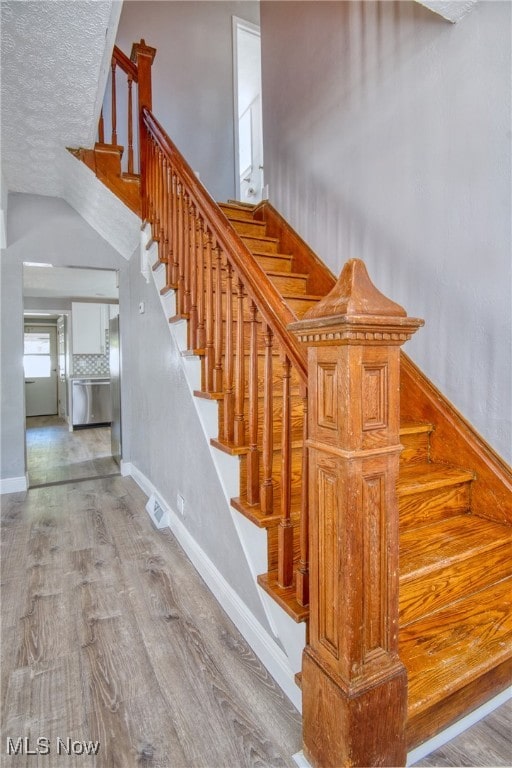 stairs featuring a textured ceiling and wood-type flooring