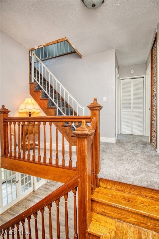 stairs featuring a textured ceiling and carpet flooring