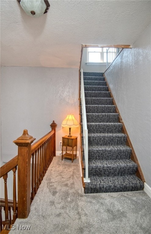 stairs featuring a textured ceiling and carpet flooring