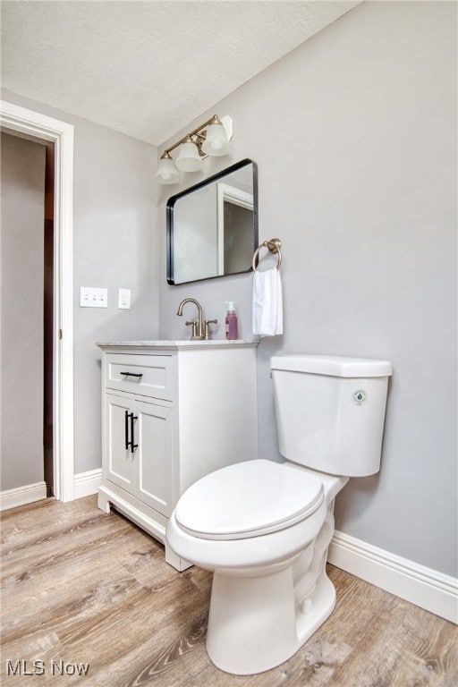 bathroom featuring hardwood / wood-style floors, toilet, a textured ceiling, and vanity