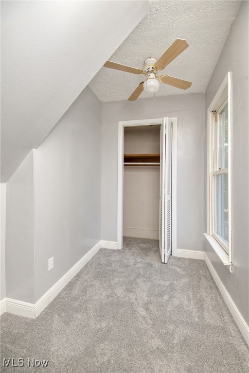 unfurnished bedroom featuring a textured ceiling, ceiling fan, light carpet, and multiple windows