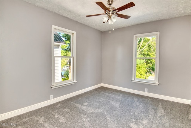 empty room with a textured ceiling, plenty of natural light, ceiling fan, and carpet