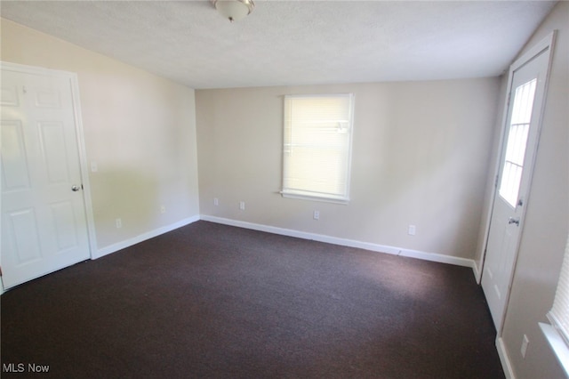 empty room with a textured ceiling and dark colored carpet