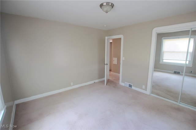 unfurnished bedroom with light carpet and a closet