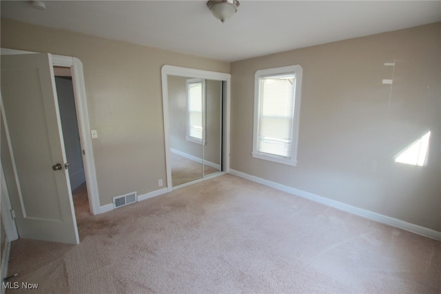 unfurnished bedroom featuring light carpet and a closet