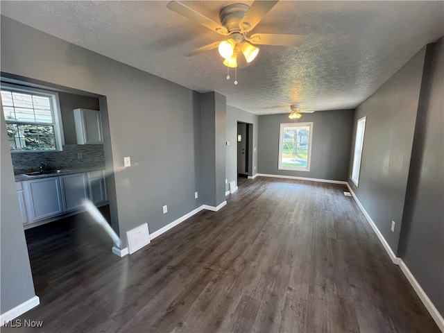 unfurnished living room featuring a textured ceiling, ceiling fan, dark hardwood / wood-style floors, and sink