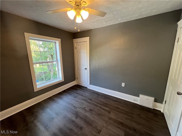 unfurnished room featuring dark wood-type flooring, ceiling fan, and a textured ceiling