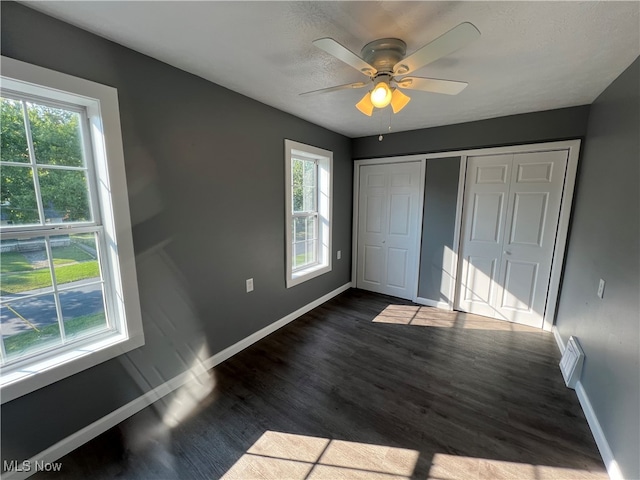 unfurnished bedroom featuring a closet, ceiling fan, dark hardwood / wood-style floors, and a textured ceiling