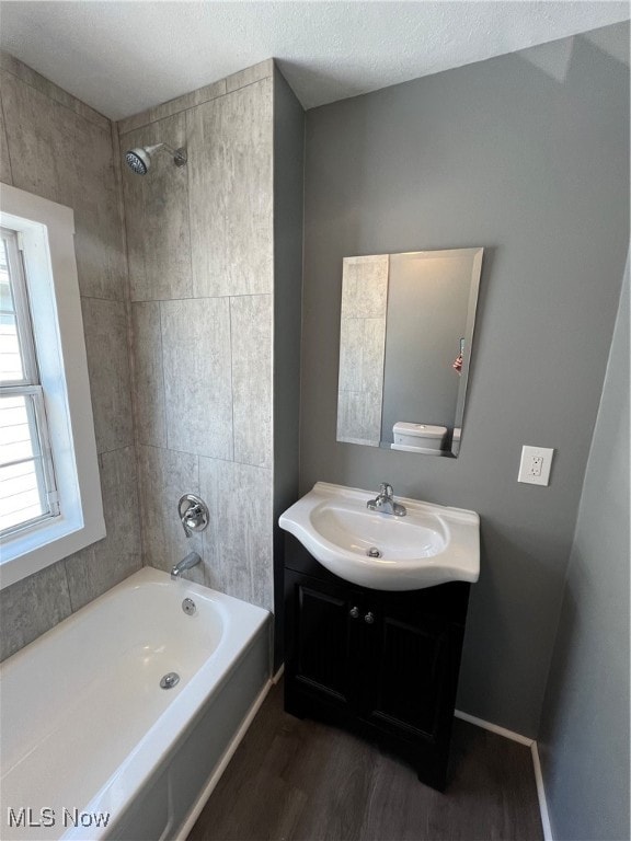 bathroom with tiled shower / bath, vanity, a textured ceiling, and hardwood / wood-style floors