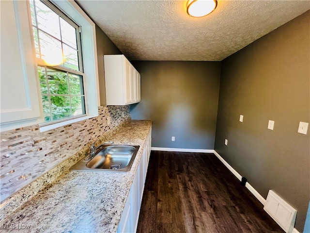 kitchen featuring white cabinets, a healthy amount of sunlight, sink, and light stone countertops