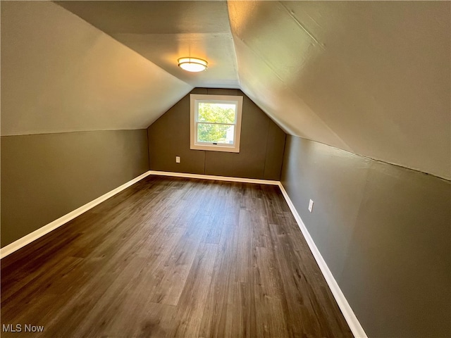 bonus room with dark wood-type flooring and vaulted ceiling