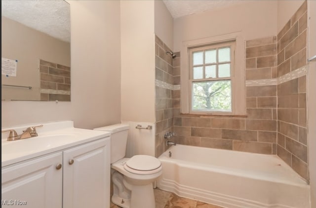 full bathroom featuring tiled shower / bath, vanity, toilet, and a textured ceiling