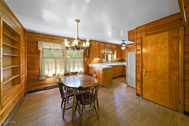 dining room with built in shelves, a chandelier, wood walls, and dark hardwood / wood-style floors