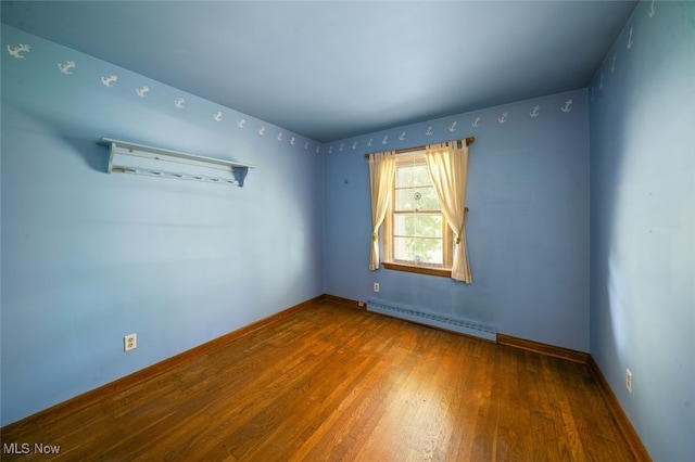 unfurnished room featuring baseboard heating and hardwood / wood-style floors