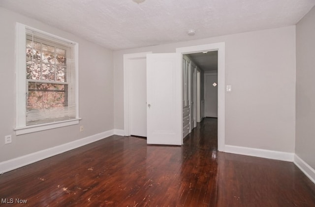 empty room featuring a textured ceiling and dark wood-type flooring