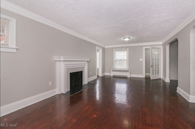 unfurnished living room with radiator heating unit, dark wood-type flooring, a textured ceiling, and crown molding