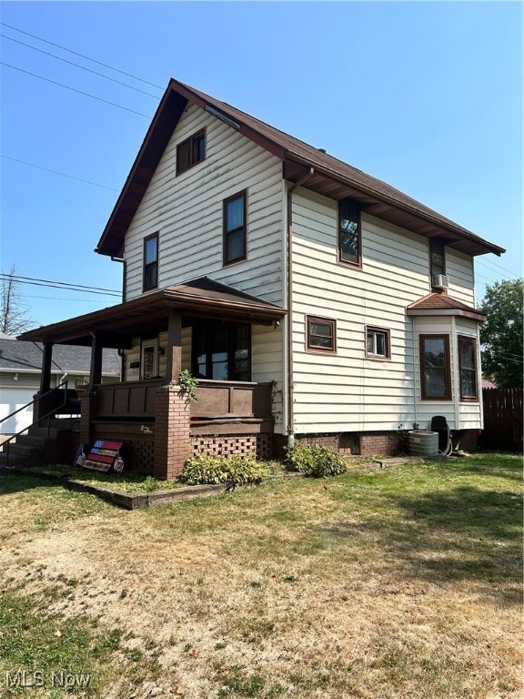 back of house featuring covered porch and a lawn