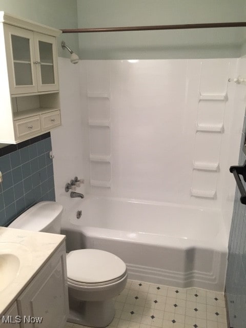 full bathroom featuring toilet, tile patterned flooring, vanity, shower / bathing tub combination, and tile walls