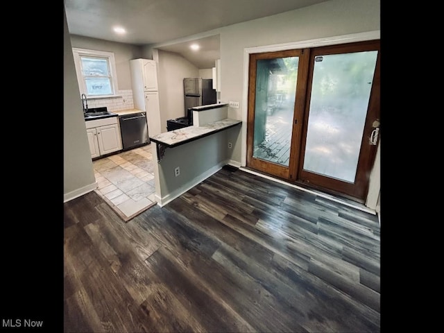 kitchen with appliances with stainless steel finishes, dark wood-type flooring, sink, decorative backsplash, and white cabinetry