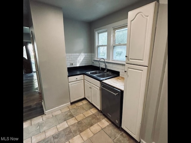 kitchen with tasteful backsplash, light tile patterned floors, dishwasher, sink, and white cabinets