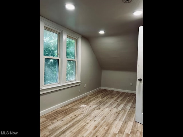 bonus room featuring light wood-type flooring, lofted ceiling, and plenty of natural light