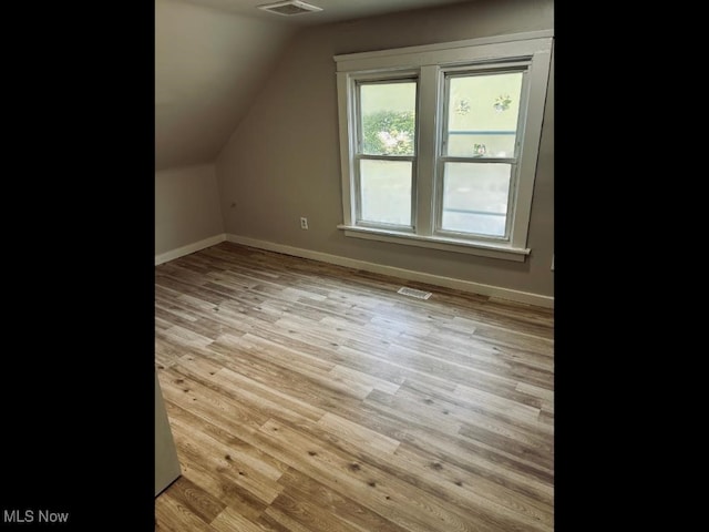 bonus room with lofted ceiling and light wood-type flooring