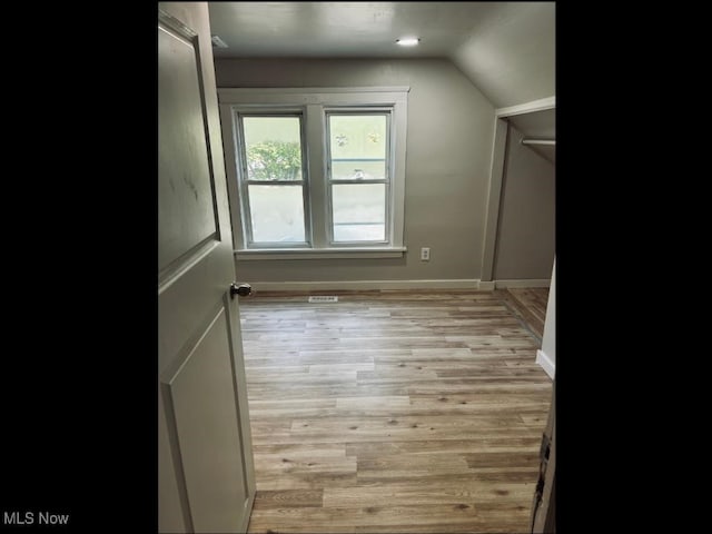 additional living space with vaulted ceiling and light wood-type flooring