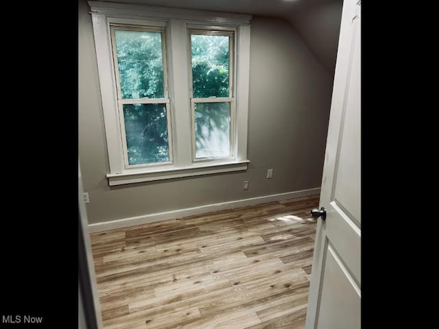 additional living space with vaulted ceiling and light hardwood / wood-style flooring