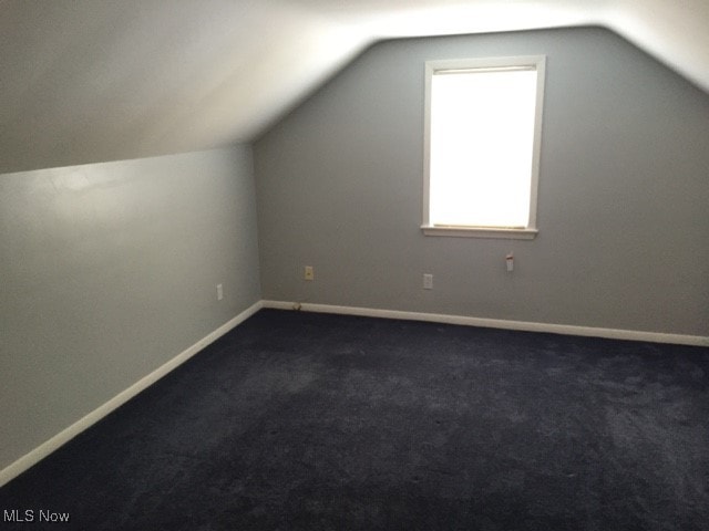 bonus room featuring dark carpet and vaulted ceiling