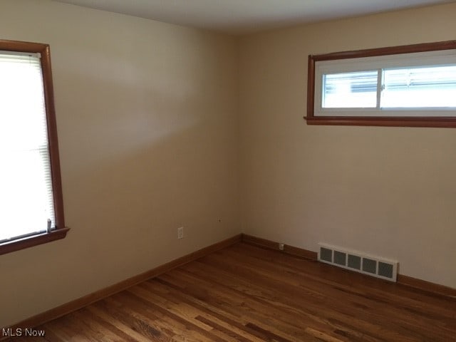 unfurnished room with dark wood-type flooring and plenty of natural light