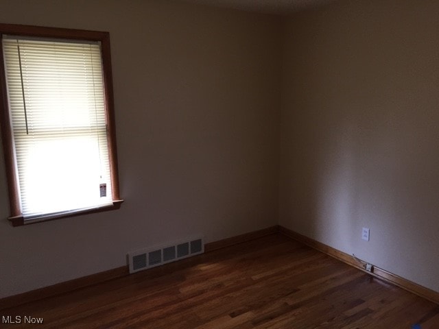 unfurnished room with dark wood-type flooring