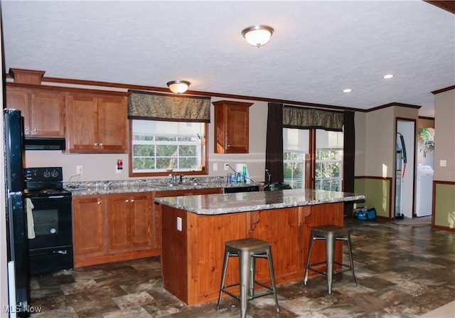 kitchen featuring a center island, black appliances, a wealth of natural light, and a breakfast bar area