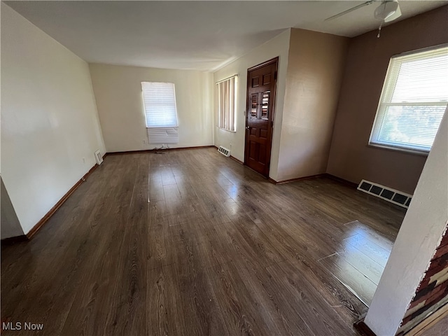 spare room featuring dark wood-type flooring, ceiling fan, and a healthy amount of sunlight